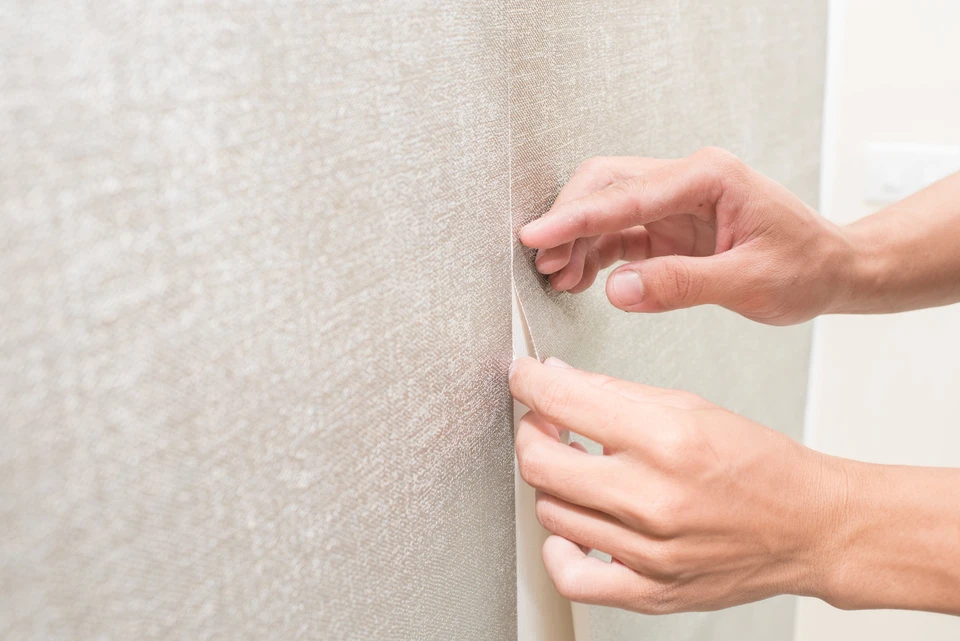 Un homme à la main pose du papier peint sur le mur