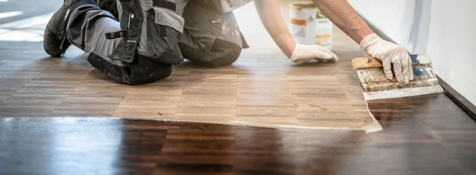 Homme en tenue de travail installant un revêtement de sol dans un intérieur résidentiel moderne