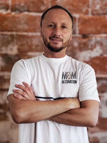 Un peintre professionnel en tenue bleue applique de la peinture blanche sur un mur intérieur à l'aide d'un rouleau à peinture